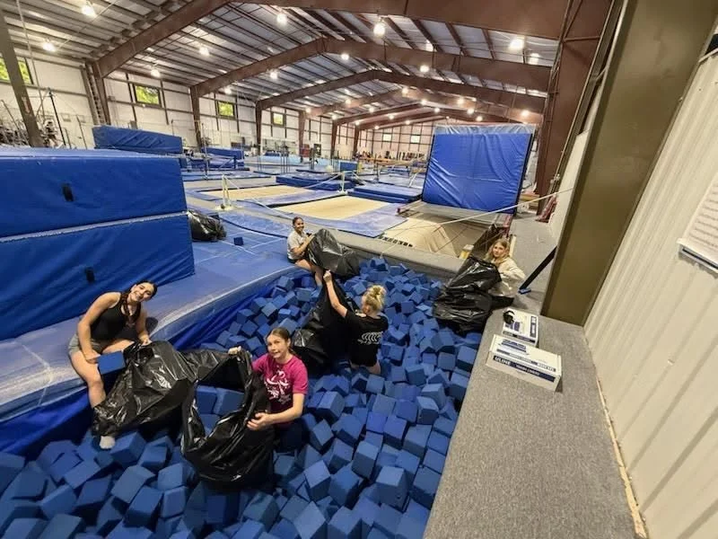 Gymnasts in the Scamps foam pit, with mats and training equipment around them