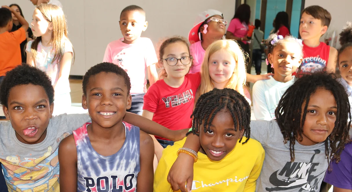 A group of smiling kids posing together in the Club gym