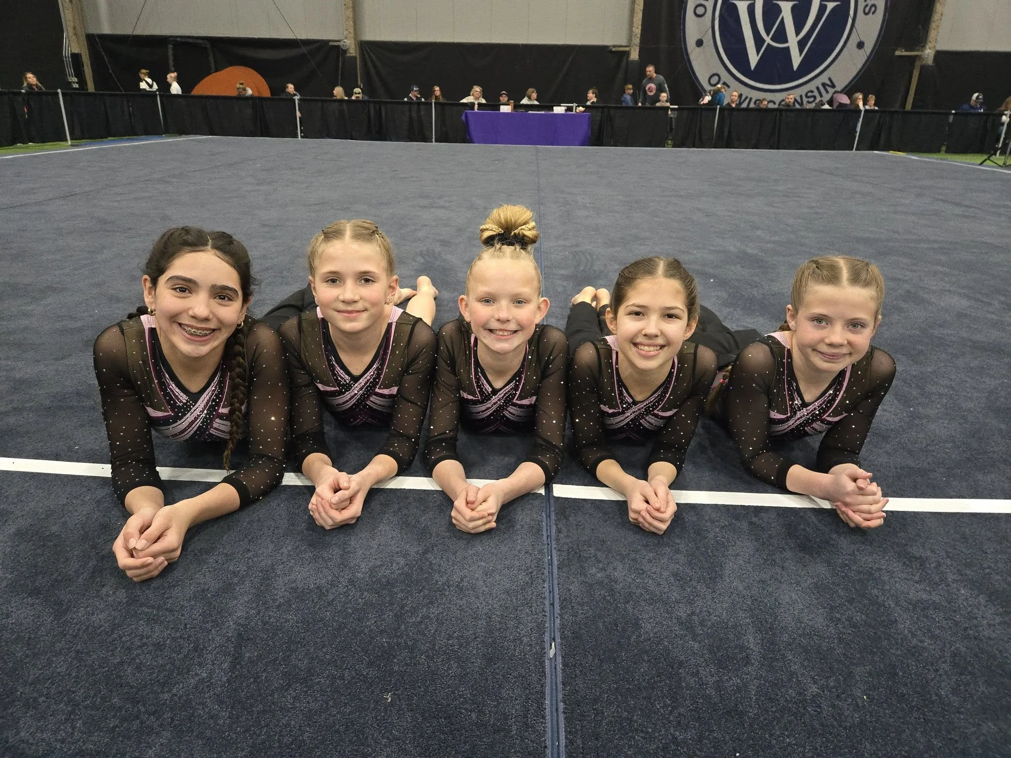 Scamps competitive team gymnasts lying on the competition floor and smiling