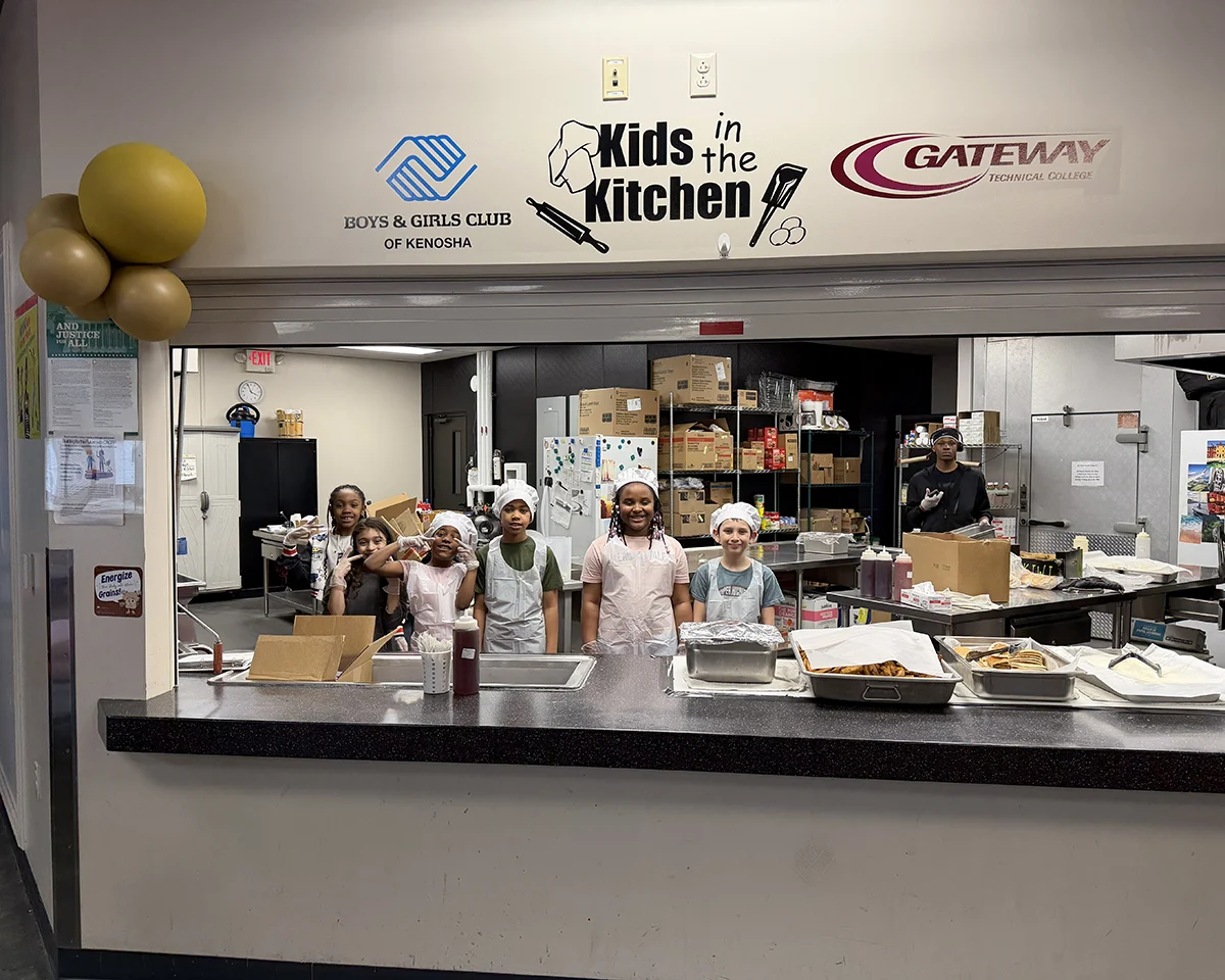 Club members in chef hats behind the Kids in the Kitchen counter in the Club kitchen