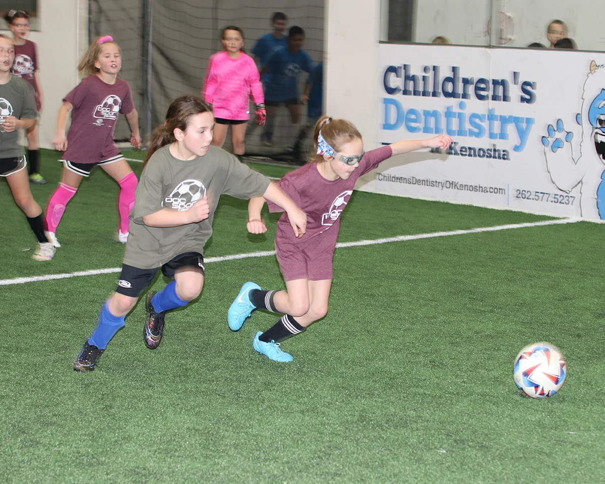 Kids racing for the ball during an indoor soccer game on the turf field